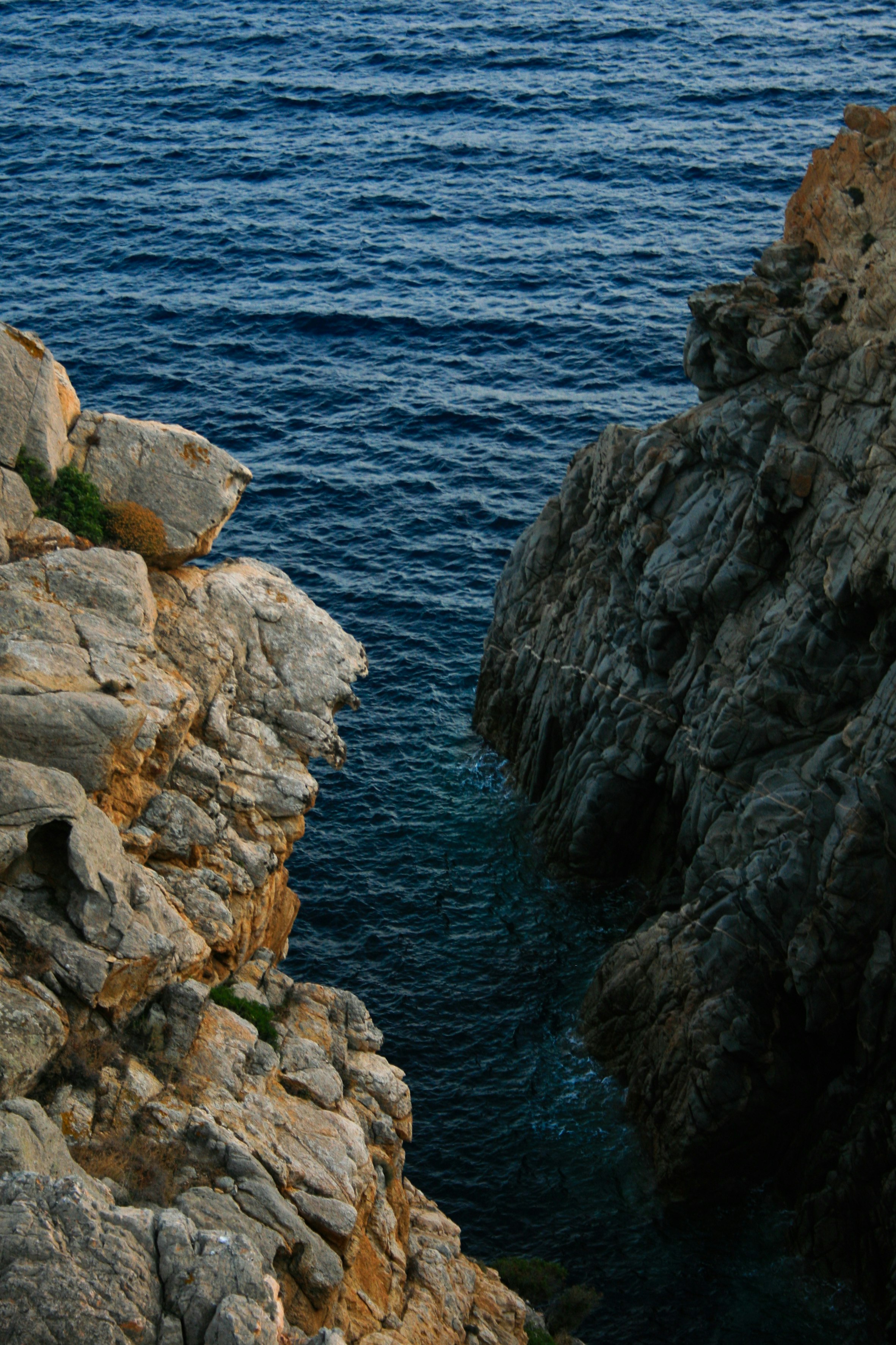 brown rocky mountain beside blue sea during daytime